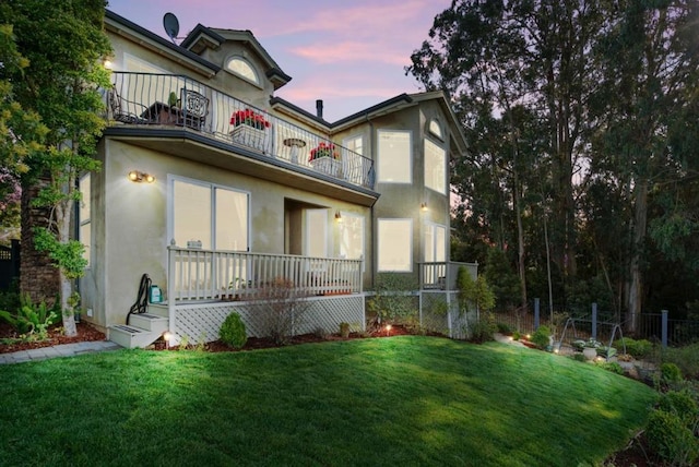 view of front of home featuring a lawn and a balcony