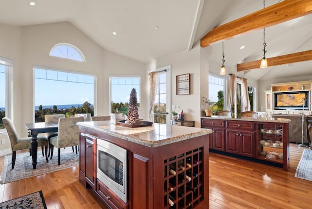 kitchen featuring stainless steel microwave, a healthy amount of sunlight, hanging light fixtures, and a kitchen island