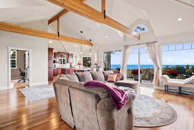 living room with a water view, beam ceiling, high vaulted ceiling, and light wood-type flooring