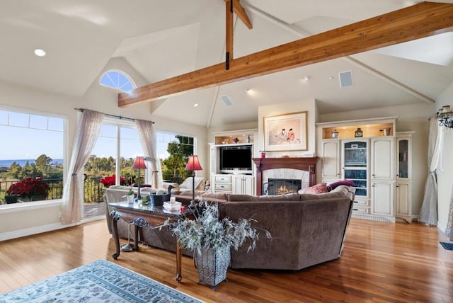 living room with beamed ceiling, a fireplace, high vaulted ceiling, and light hardwood / wood-style flooring