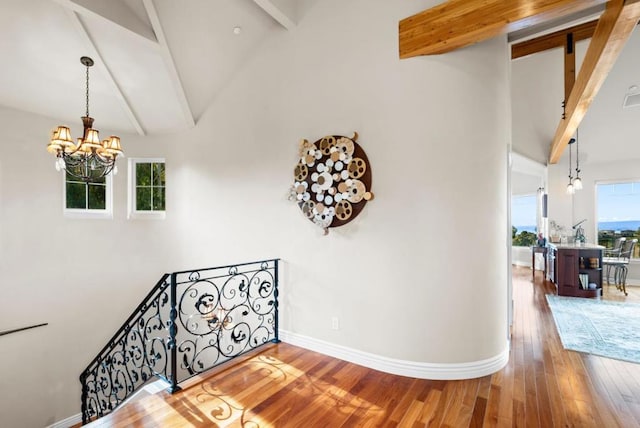 stairway with beamed ceiling, wood-type flooring, an inviting chandelier, and high vaulted ceiling