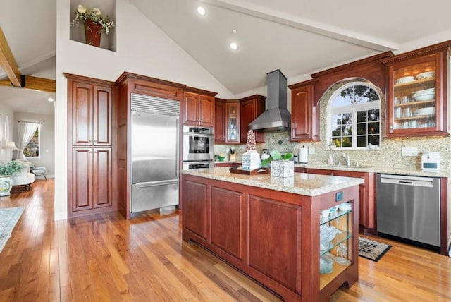 kitchen featuring appliances with stainless steel finishes, backsplash, light hardwood / wood-style floors, and wall chimney exhaust hood