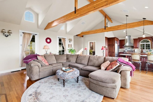 living room featuring high vaulted ceiling, a wealth of natural light, light hardwood / wood-style floors, and beamed ceiling