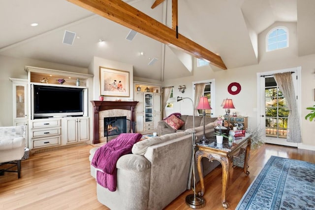 living room featuring high vaulted ceiling, light wood-type flooring, and beam ceiling