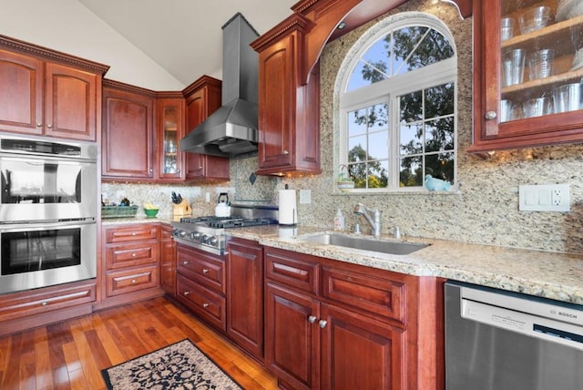 kitchen featuring lofted ceiling, wall chimney range hood, sink, appliances with stainless steel finishes, and dark hardwood / wood-style flooring