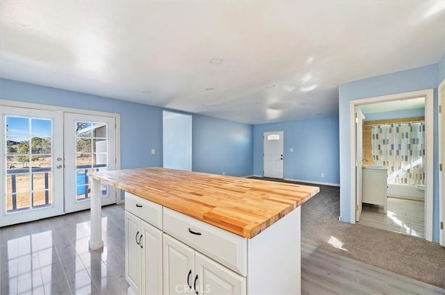 kitchen featuring white cabinetry, french doors, a kitchen island, and wood counters