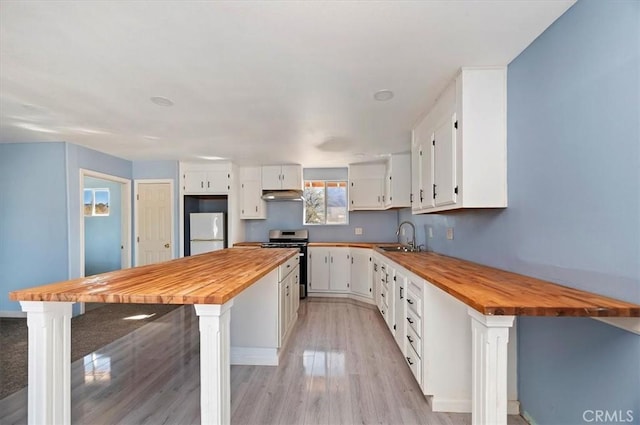 kitchen with wood counters, white refrigerator, white cabinets, and stainless steel range