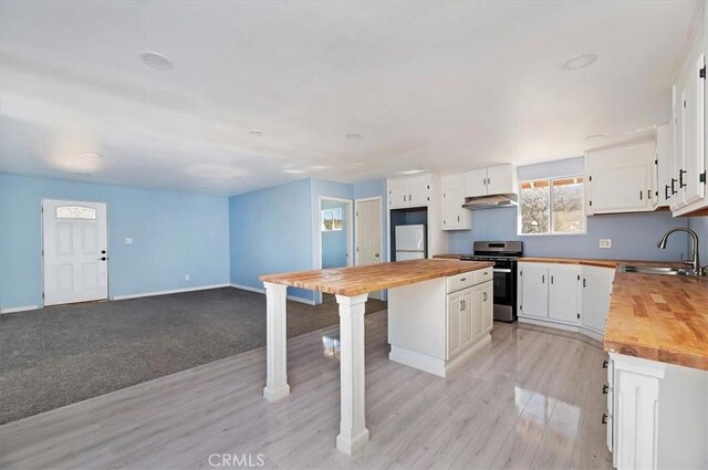 kitchen featuring butcher block counters, sink, stainless steel range, a kitchen island, and white cabinetry