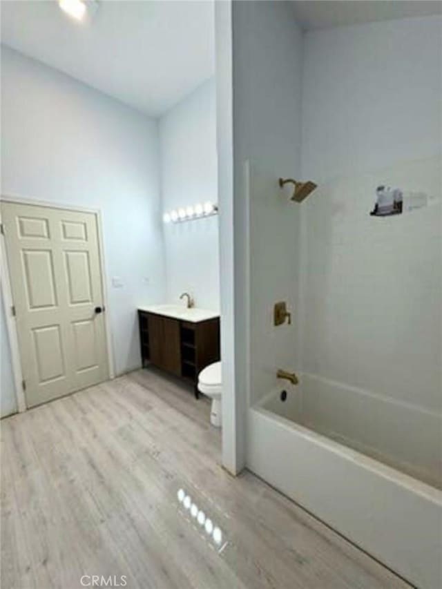 full bathroom featuring wood-type flooring, vanity, bathing tub / shower combination, and toilet