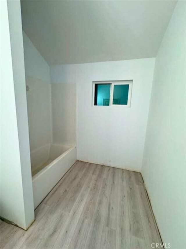 bathroom with wood-type flooring and a tub