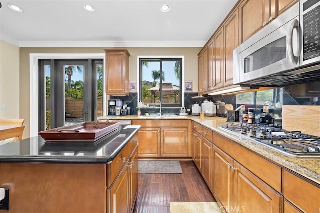 kitchen featuring stainless steel appliances, a healthy amount of sunlight, ornamental molding, and sink