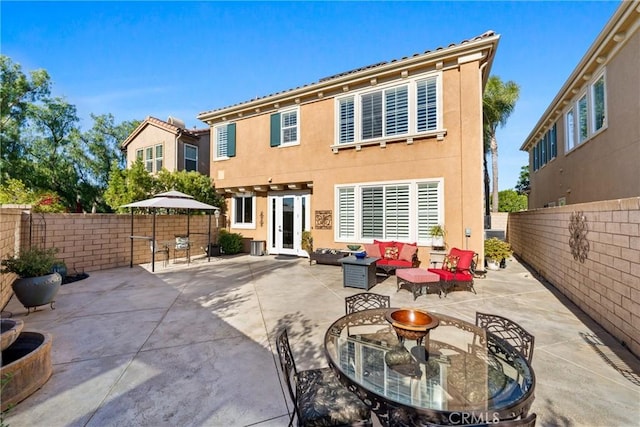 rear view of property with a patio area and an outdoor living space with a fire pit