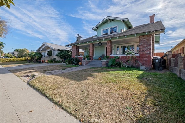 bungalow-style home with a front yard and covered porch