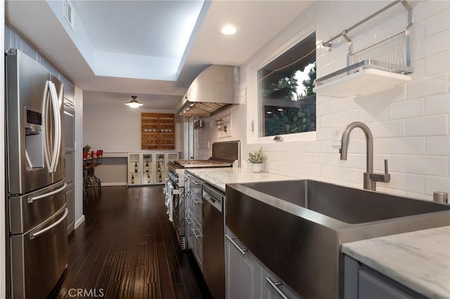 kitchen with range hood, appliances with stainless steel finishes, backsplash, and sink