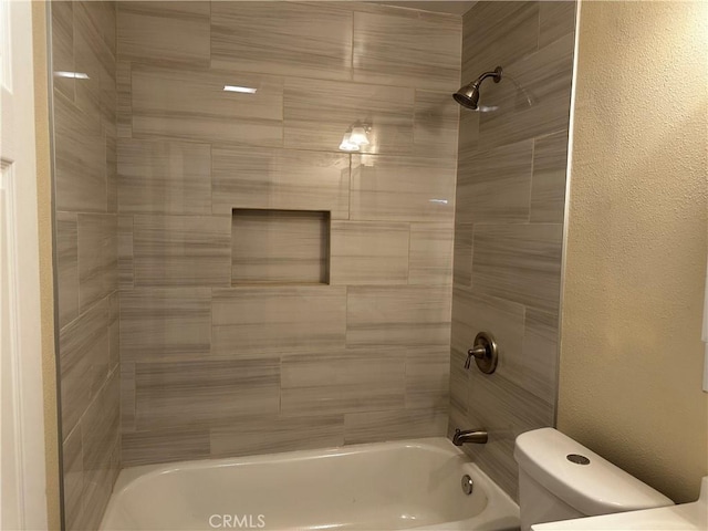 bathroom featuring toilet and tiled shower / bath