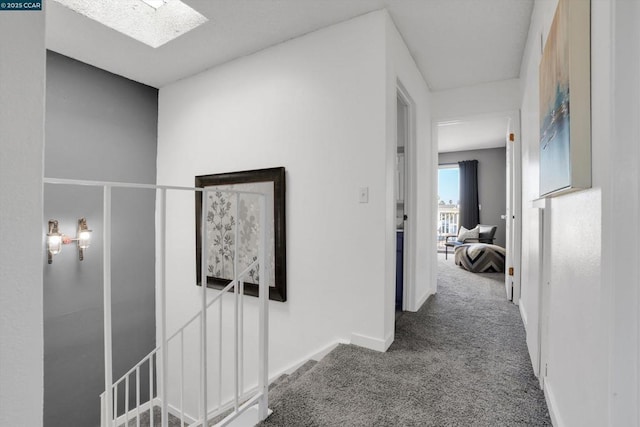 hallway with a skylight and carpet flooring