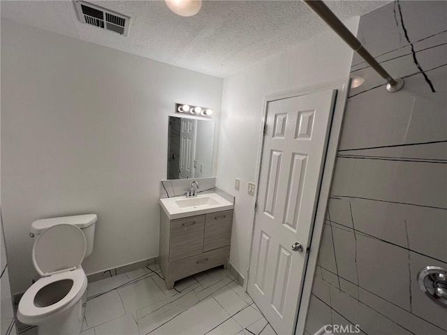 bathroom with a textured ceiling, toilet, and vanity