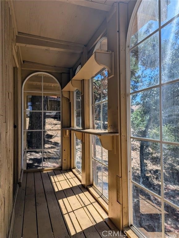 unfurnished sunroom with beam ceiling