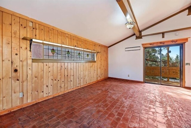 empty room with vaulted ceiling with beams and wooden walls