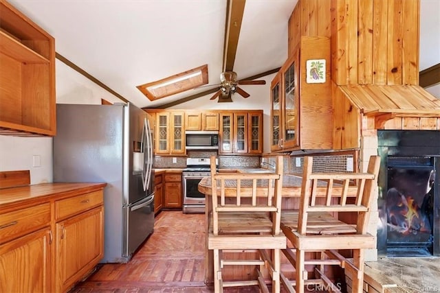 kitchen featuring ceiling fan, stainless steel appliances, tasteful backsplash, vaulted ceiling with beams, and parquet flooring