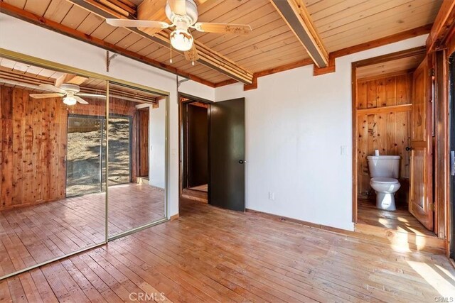 unfurnished bedroom with ceiling fan, a closet, beamed ceiling, and light hardwood / wood-style floors