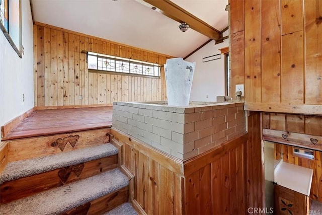 interior space featuring carpet, lofted ceiling with beams, and wood walls