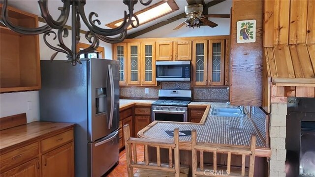 kitchen featuring ceiling fan, sink, lofted ceiling, decorative backsplash, and appliances with stainless steel finishes