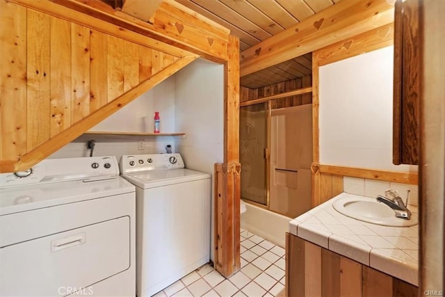 laundry room with sink, washer and dryer, light tile patterned floors, wooden ceiling, and wood walls