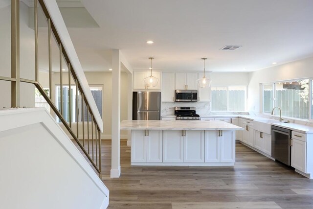 kitchen featuring a center island, pendant lighting, sink, appliances with stainless steel finishes, and white cabinets