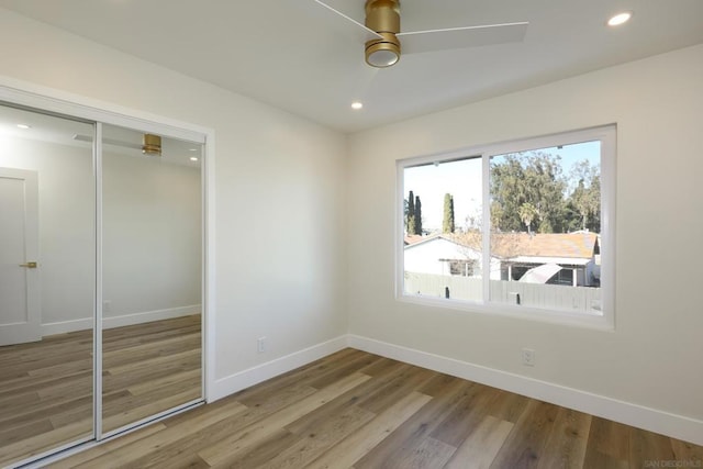 unfurnished bedroom with ceiling fan, hardwood / wood-style floors, and a closet