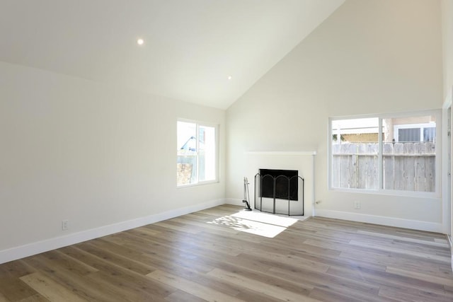 unfurnished living room featuring high vaulted ceiling, a healthy amount of sunlight, and light hardwood / wood-style floors