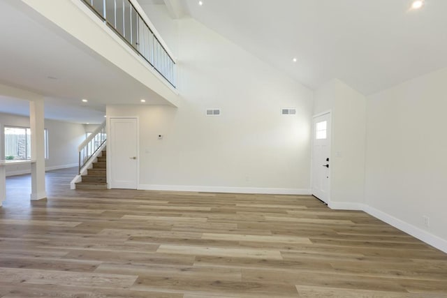 unfurnished living room with high vaulted ceiling and light hardwood / wood-style flooring