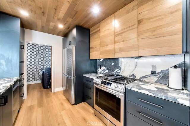 kitchen featuring light stone counters, stainless steel range with gas cooktop, and backsplash