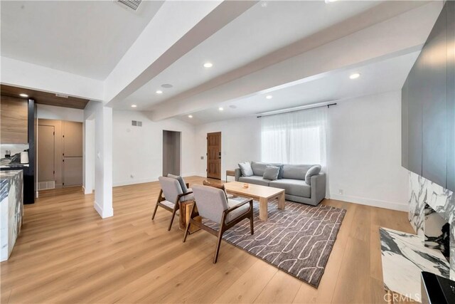 living room featuring light hardwood / wood-style floors and vaulted ceiling with beams