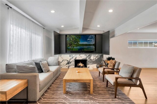 cinema featuring lofted ceiling with beams, a high end fireplace, and hardwood / wood-style flooring