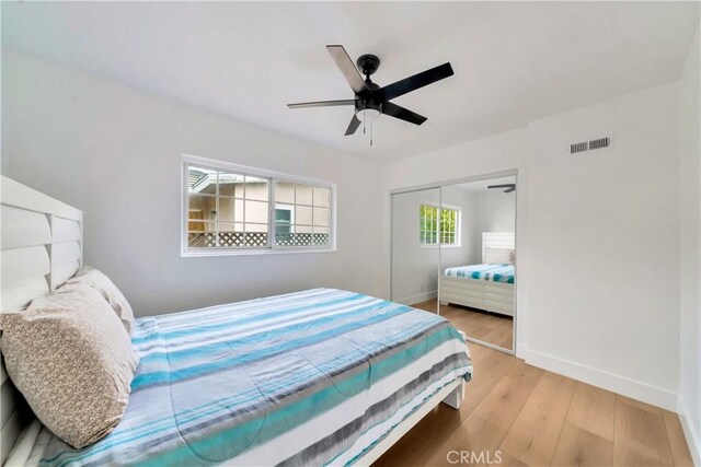 bedroom with a closet, light hardwood / wood-style floors, and ceiling fan