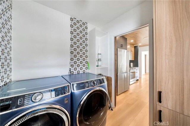 laundry area with washer and dryer and light hardwood / wood-style floors