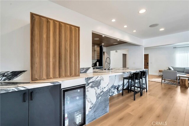 kitchen with light hardwood / wood-style floors, sink, and beverage cooler