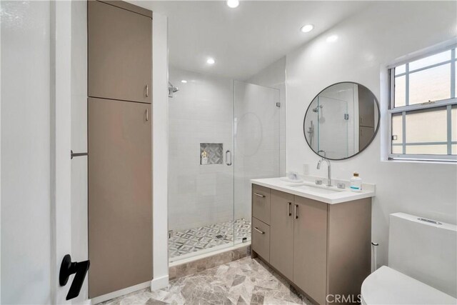 bathroom featuring toilet, a shower with shower door, and vanity