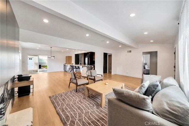 living room featuring vaulted ceiling with beams and light wood-type flooring