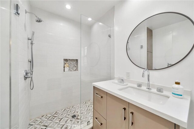 bathroom featuring tiled shower and vanity