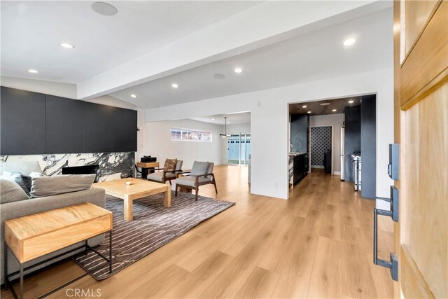 living room featuring light wood-type flooring and vaulted ceiling with beams