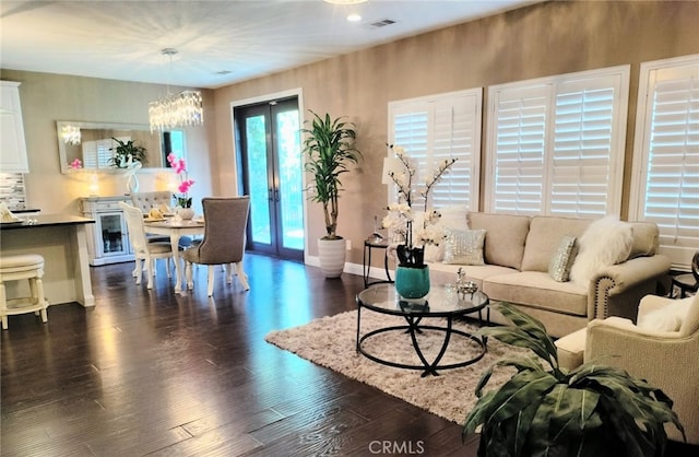 living room with dark wood-type flooring, french doors, and a notable chandelier