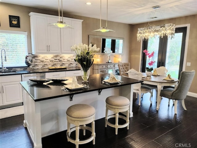 kitchen featuring white cabinetry, a center island, backsplash, and decorative light fixtures