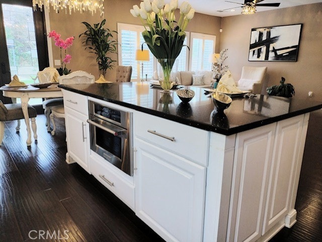 kitchen with ceiling fan, dark wood-type flooring, white cabinetry, and oven