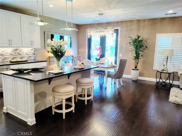 kitchen featuring white cabinetry, decorative backsplash, dark hardwood / wood-style flooring, pendant lighting, and a center island