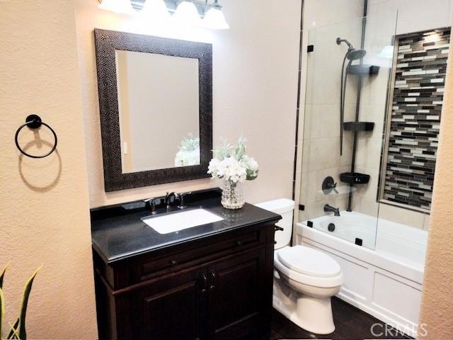 full bathroom with tiled shower / bath combo, vanity, and toilet