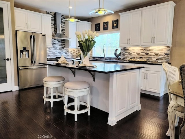 kitchen featuring decorative light fixtures, white cabinets, wall chimney exhaust hood, and high end fridge