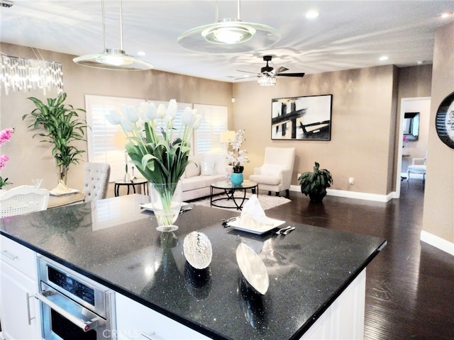 kitchen featuring wall oven, dark stone countertops, white cabinets, and hanging light fixtures