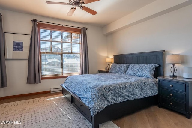 bedroom featuring light hardwood / wood-style flooring, ceiling fan, and a baseboard heating unit